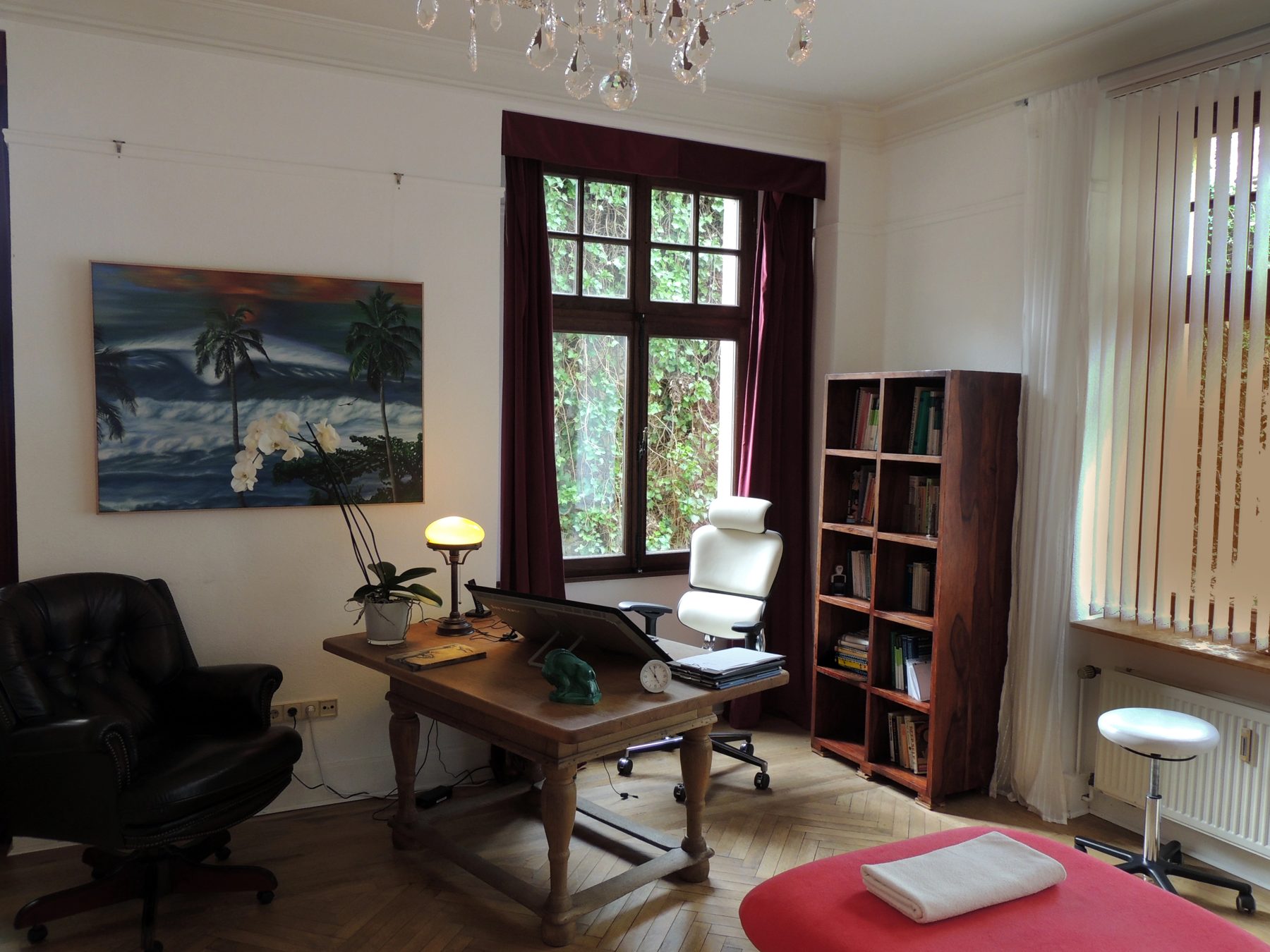 Behandlungsraum der Chiropraxis Köln: Holztisch, Behandlungsbank, Blick ins Grüne